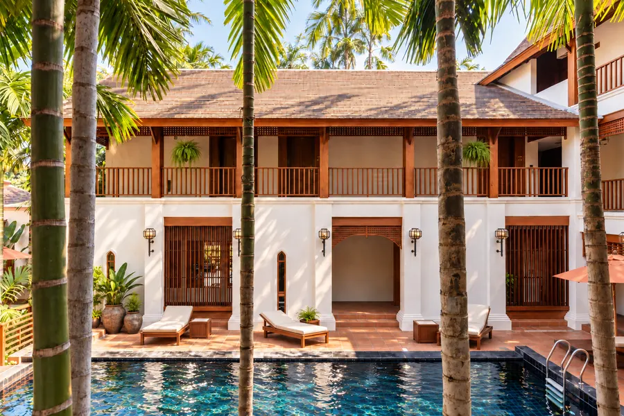 A white guesthouse with wooden balconies and a pool